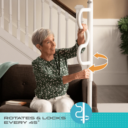 An older woman sits on a couch, holding the Stander Wonder Pole HD - Bariatric Fall Prevention Safety Pole. An arrow shows the grab bar rotates and locks every 45° for fall prevention.
