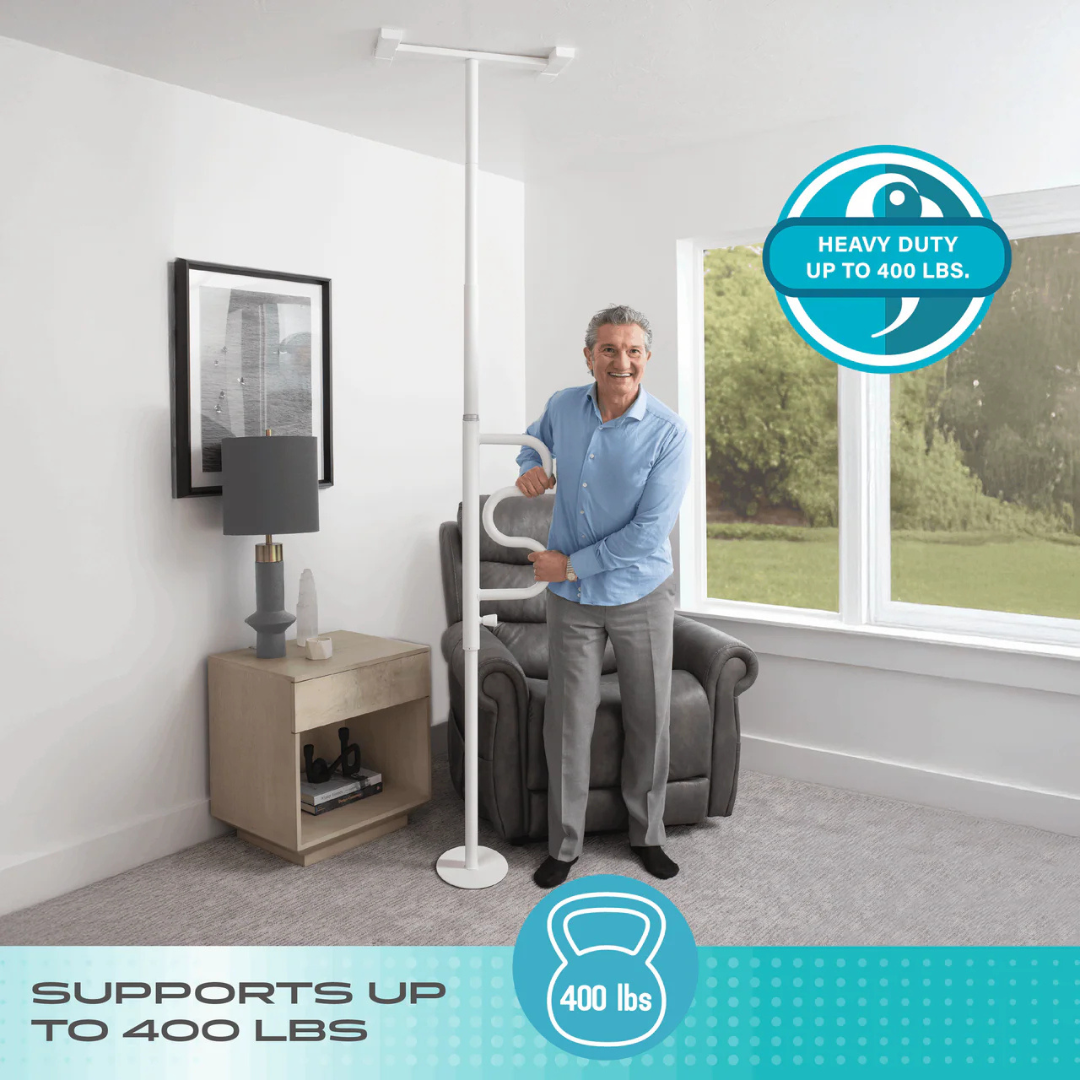 Smiling older man stands next to the Stander Wonder Pole HD - Bariatric Fall Prevention Safety Pole in his living room. This heavy-duty white tension pole supports up to 400 lbs, providing reliable stability near his recliner and side table.