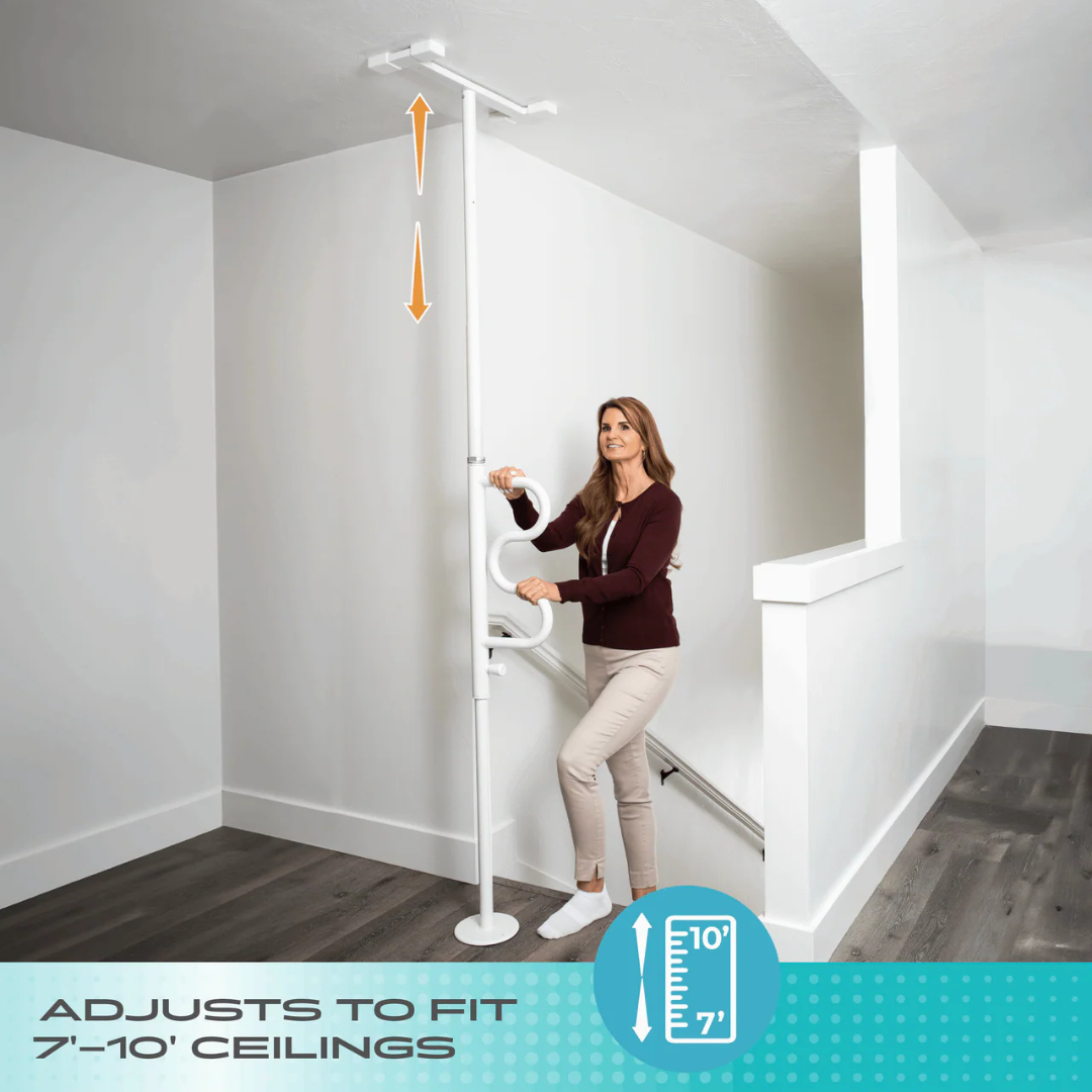 A woman demonstrates the Stander Wonder Pole HD - Bariatric Fall Prevention Safety Pole, a white floor-to-ceiling tension pole with handle, installed by stairs. Text: Adjusts to fit 7-10' ceilings; adjustable height icon for fall prevention.