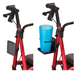 Two side-by-side images show a red mobility scooter; the left image features an empty folding cup holder from Nova Medical Star Series Rollator Accessories attached to the frame, while the right image displays a blue cylindrical container placed in it.