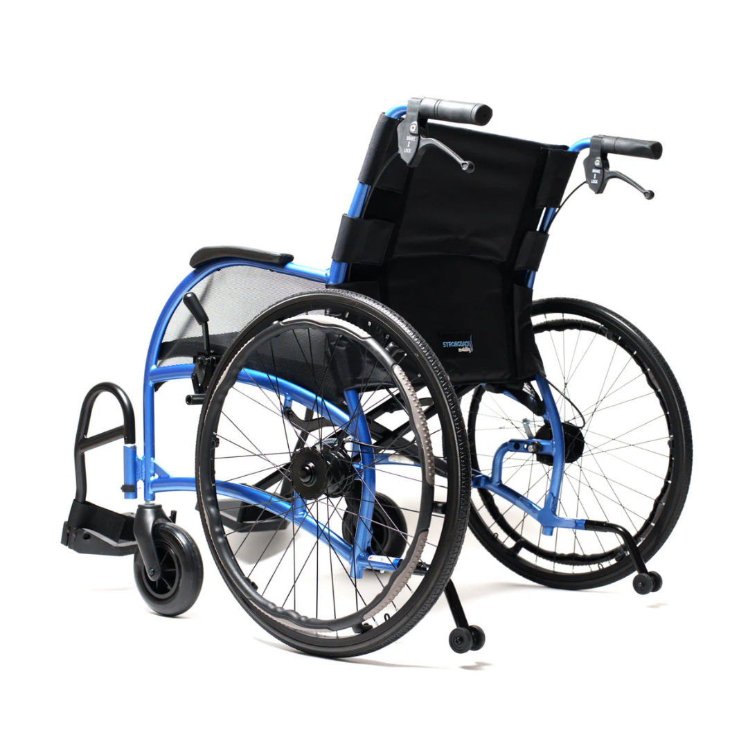 The Strongback Mobility 24HD Heavy Duty Wheelchair is shown against a white background. It features a blue frame, large rear wheels, black cushioning, visible handles and footrests. The angled view highlights its lightweight build and ergonomic design.