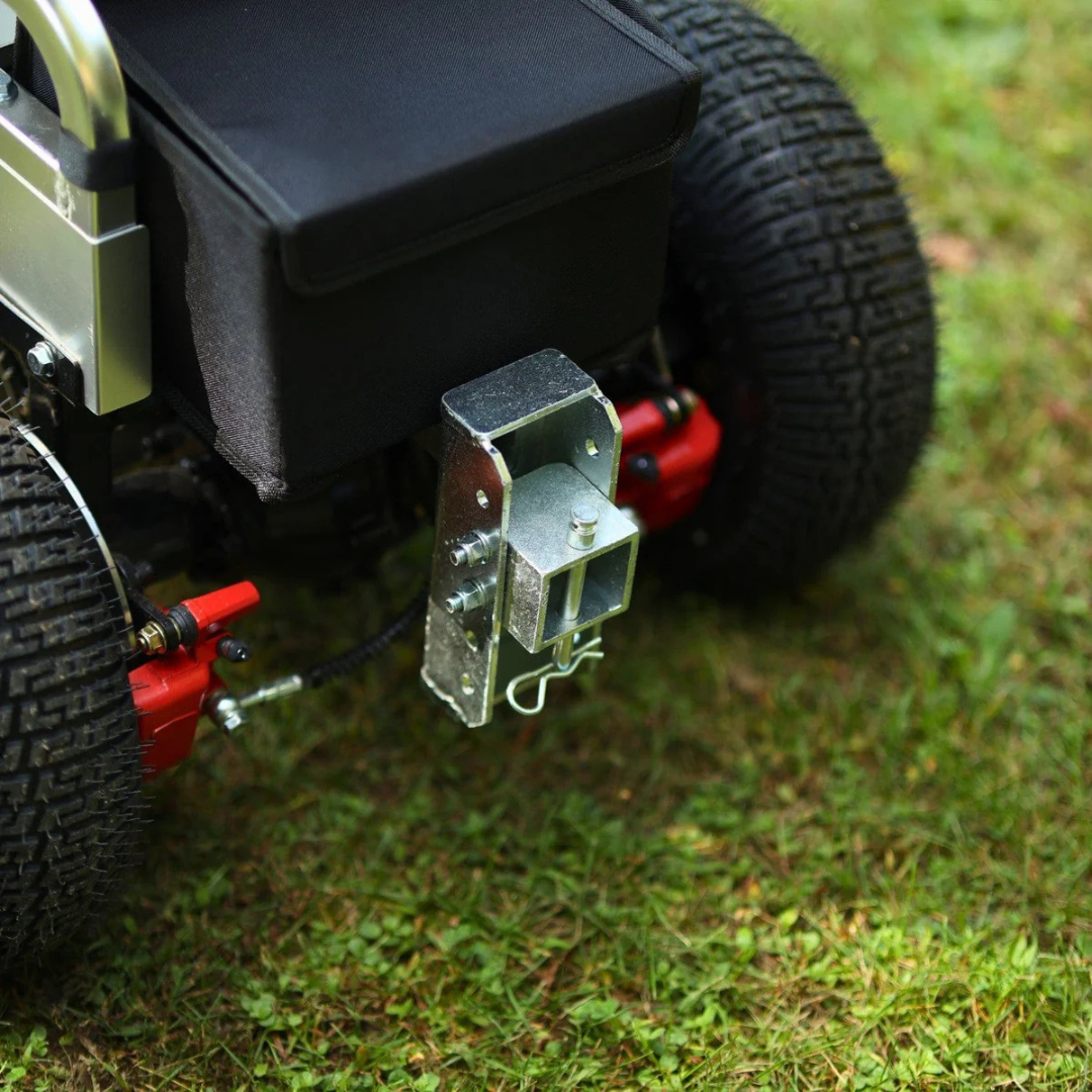 Close-up of a metal hitch attached to the rear of a rugged wheelchair with large treaded wheels, ready for use with the SuperHandy Tugger Tow Tractor - Powerful Towing Scooter on grassy ground.
