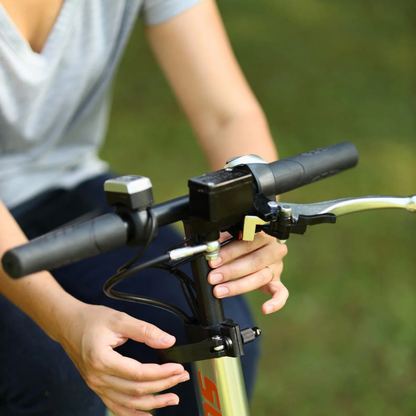 A person adjusts a bicycle's handlebars outdoors, wearing a light gray t-shirt. In the grassy background, the SuperHandy Tugger Tow Tractor - Powerful Towing Scooter is visible.