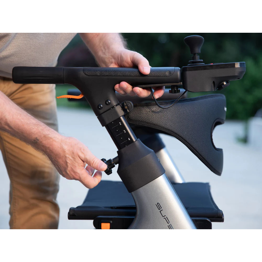 A person adjusts the height of the Superpi W1 Electric Wheelchair Rollator’s handlebar with a knob, keeping one hand on the handle and the other on the adjustment. The rollator features a control panel and padded armrest.