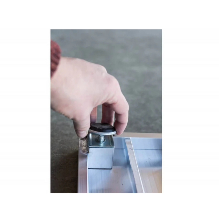 A hand adjusts a metal leveling foot on a gray aluminum frame, placed on a smooth concrete floor, demonstrating the precision required for setting up adjustable legs on an EZ-Access TRANSITIONS® Angled Entry Ramp.