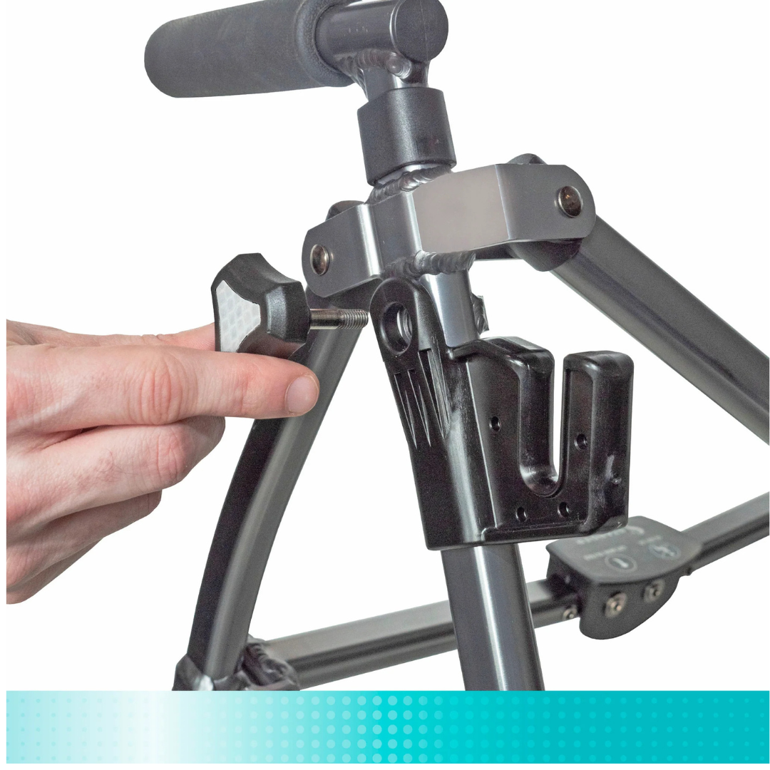 A hand adjusts a knob on a metal frame of a Stander walker, likely to attach or secure the Tray Accessory for Stander Walkers & Rollators.