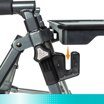 Close-up of the folding mechanism and attachment hook on a Stander walker, with an orange arrow pointing to the hook beneath the black Tray Accessory For Stander Walkers & Rollators.