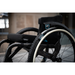 A modern wheelchair showcasing Triumph Mobility reTyre Traction Skins is focused upon, featuring sturdy wheels with advanced puncture protection. It boasts a black cushioned seat and is set indoors against a blurred background, emphasizing its contemporary design.