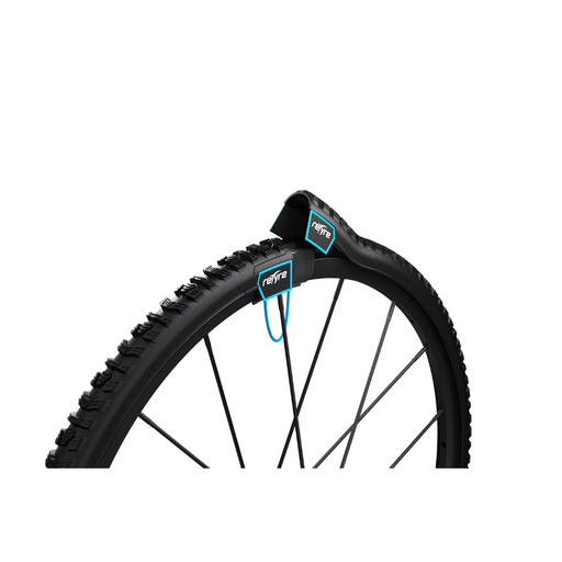 A close-up view of a black bicycle wheel showcases the Triumph Mobility reTyre Traction Skins, a mounted device with turquoise accents. The rugged tread pattern offers exceptional off-road traction and is positioned near the top of the wheel.