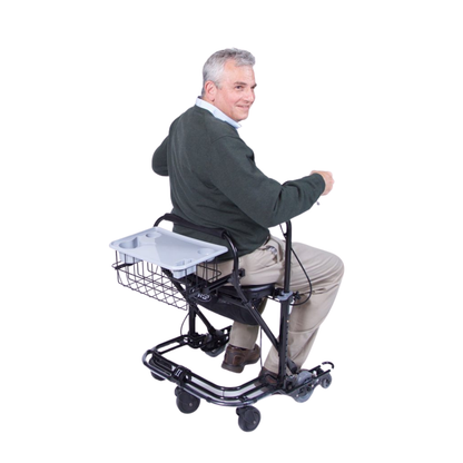An older man with gray hair in a green sweater and beige pants sits on a mobility scooter with the In-Step Home Caddy Kit for U-Step Walker attached to the back, facing slightly away and smiling.
