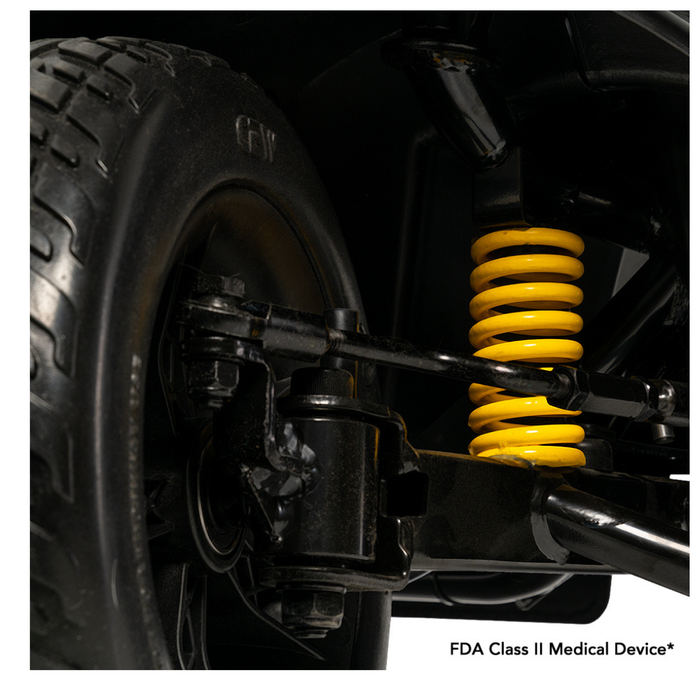 Close-up of a black wheel and suspension system with a bright yellow coil spring, showing mechanical components and EZ Turn Technology on the Pride Mobility Victory® Platinum Bariatric 4-Wheel Scooter. Text at bottom: FDA Class II Medical Device.*.