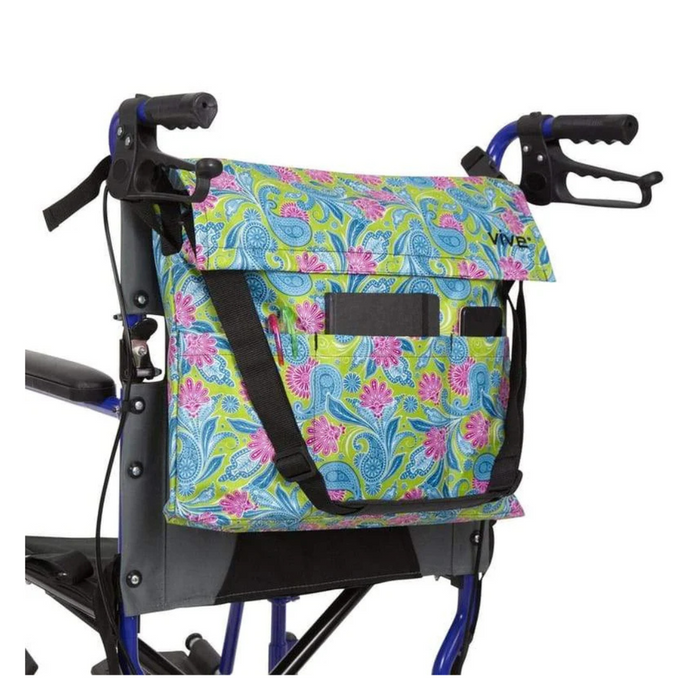 A vibrant floral bag in waterproof nylon with pink, green, and blue paisley patterns is attached to the back of a blue walker. Named the Vive Health Portable Mobility Bag with Shoulder Strap, it includes adjustable straps and two black handles. The walker has black hand grips.