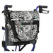 A Vive Health Portable Mobility Bag with Shoulder Strap, crafted from waterproof nylon in a black and white abstract pattern, is attached to the back of a blue and black wheelchair. The bag has adjustable black straps and colorful tabs on the top flap for a vibrant touch.