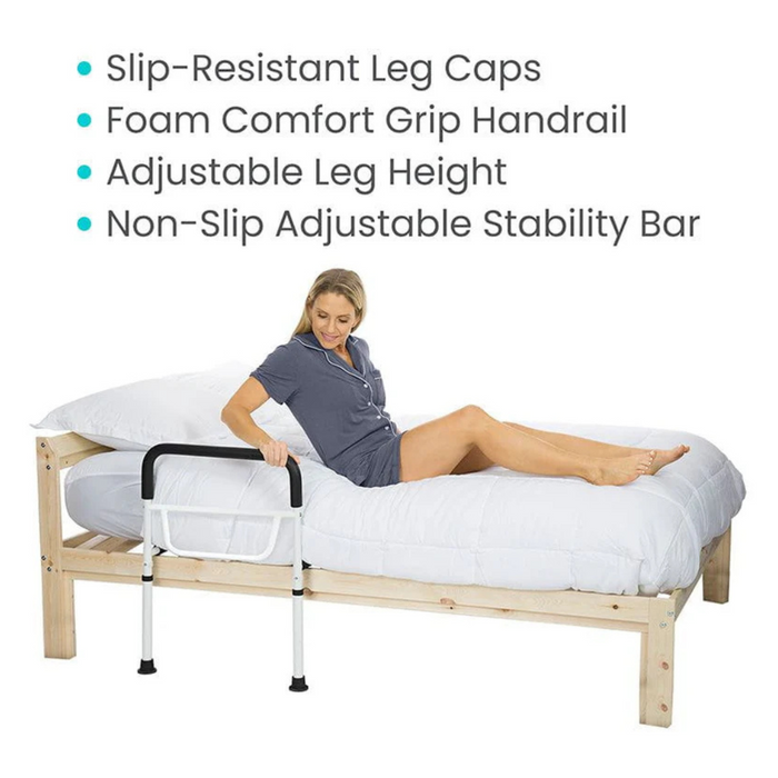 A woman sits on a bed using the Vive Health Bed Rail - Height Adjustable for assistance, showcasing its features: slip-resistant leg caps, foam comfort grip handrail, adjustable height legs, and a non-slip adjustable stability bar.