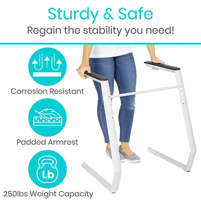 A person uses the Vive Health Stand Alone Rail, featuring a modern design with corrosion resistance and a durable steel frame. This white support frame with padded armrests offers sturdy and safe assistance, boasting a weight capacity of 250 lbs for reliable stability anywhere in the home.