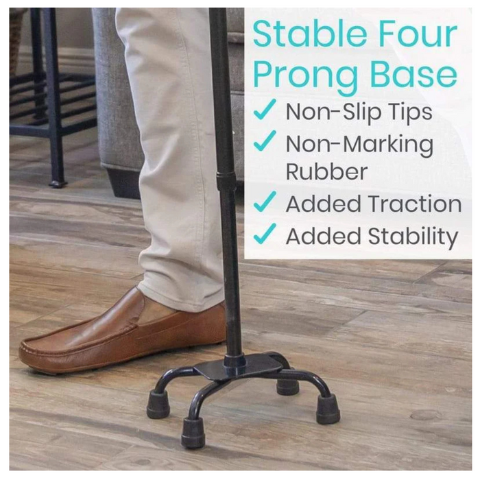 A person in beige pants and brown shoes uses the Vive Health Quad Cane - Lightweight & Height Adjustable, which features a stable four-prong base on a wooden floor. The cane includes non-marking rubber tips for added traction and a comfort grip handle for increased support.