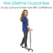 A woman in a blue cardigan and black pants smiles while using a Vive Health Carbon Fiber Quad Cane in black, with an ergonomic grip. Text above reads, Vive Lifetime Guarantee - Purchase now with confidence.