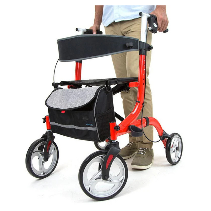 Using a Vive Health Euro-Style Everglide Rollator with a vibrant red aluminum frame, ergonomic brakes, and black storage bag, a person in a light blue shirt, beige pants, and brown shoes enjoys stability from its large wheels.