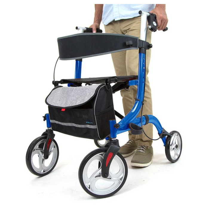 A person stands behind a blue Vive Health Euro-Style Everglide Rollator, featuring a black and gray bag, lightweight aluminum frame, large wheels, and ergonomic hand brakes. Holding the handles, the individual’s khaki pants and shoes are partially visible.