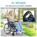 A woman in a wheelchair waves happily on a park path, wearing a beige top and blue jeans. The image showcases the XL wheels of the Vive Health Air Frame Lightweight Folding Wheelchair, designed with easy-grip tread for secure and smooth mobility.