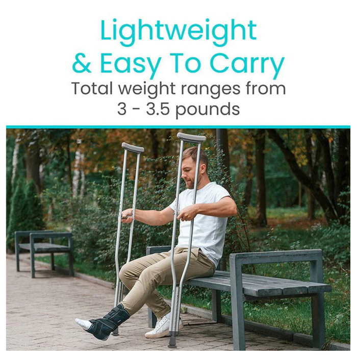 A man sits on a park bench with Vive Health Underarm Crutches, highlighting their lightweight design (3-3.5 pounds) and superior mobility support. Wearing a medical boot on his right foot, he explains how these crutches ease his recovery journey. Behind him are trees and a winding path.