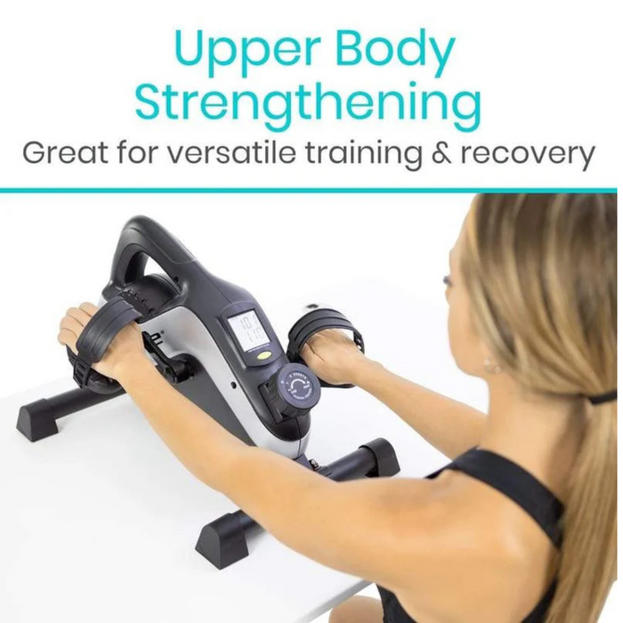 A woman uses the Vive Health Smart Magnetic Pedal Exerciser on a table. The compact design includes hand grips, a digital screen, and a magnetic resistance dial for versatile upper body strengthening and recovery.
