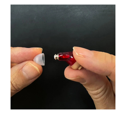 A close-up shows two hands with Vivtone Ear Tip Replacements for Super-Mini Hearing Aids: one holding a red in-ear device, the other holding a small translucent CIC dome, ready to attach the replacement ear tip.
