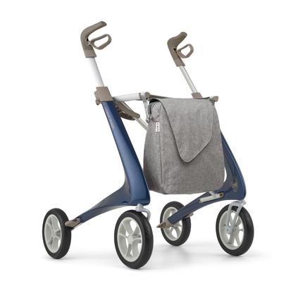 The Weekend Bag for ByAcre Carbon Fiber Rollators is a large gray fabric bag that attaches to the front, offering a stylish and functional storage solution designed to complement your modern blue and gray walker.