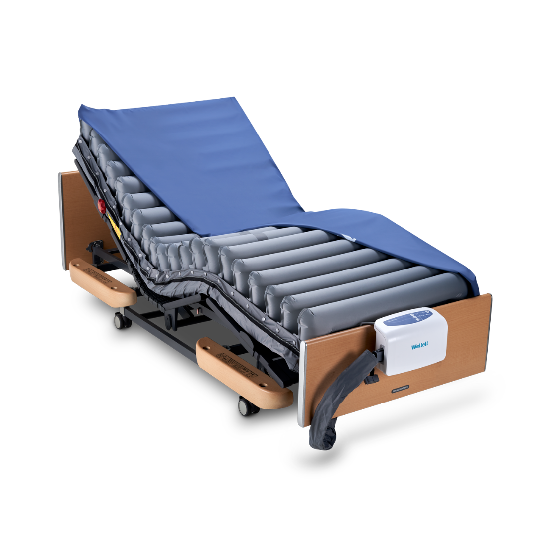 The Wellell Domus Auto G2 Bariatric Alternating Pressure and Low Air Loss System features an air mattress with blue cover, wooden side rails, white electronic control unit at the foot, and backrest in the elevated position for pressure ulcer prevention.