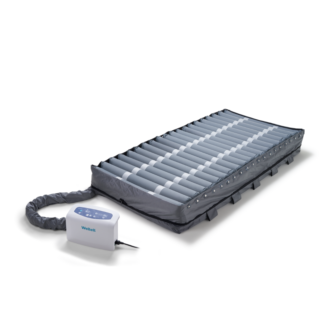 The Wellell Serene Air Alternating Pressure Mattress with True Low Air Loss features air-filled cylindrical cells and a control unit with buttons and display. The connected electric pump helps prevent pressure injuries in post-acute care settings.