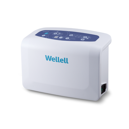 The Wellell Serene Air Alternating Pressure Mattress with True Low Air Loss is a white, rectangular medical device with rounded edges, a blue control panel on top with buttons, and the Wellll brand on the front, designed for post-acute care.