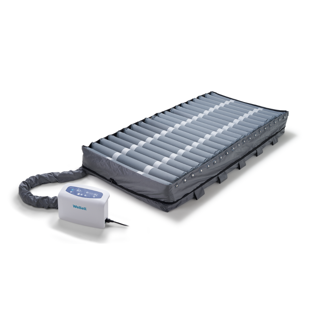 The Wellell Serene Air Alternating Pressure Mattress with True Low Air Loss features cylindrical air cells, a control unit, and a protective cover, designed to prevent pressure injuries and manage moisture in bedridden patients.