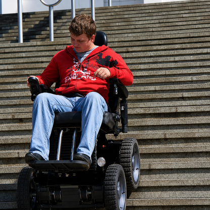 A young man cautiously descends a long outdoor staircase using the Wheelchair88 All-Terrain Stair Climbing 4x4 Recreational Electric Vehicle, gripping the controls and relying on its advanced gyro balance technology.