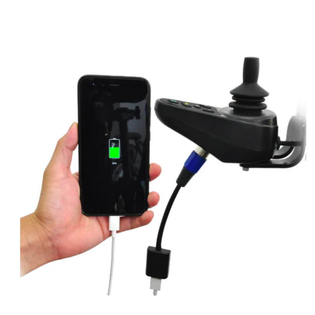 A hand holds a smartphone showing a charging icon, connected by cable to a black joystick controller—likely for the Wheelchair88 All-Terrain Stair Climbing 4x4 Recreational Electric Vehicle with gyro balance technology.