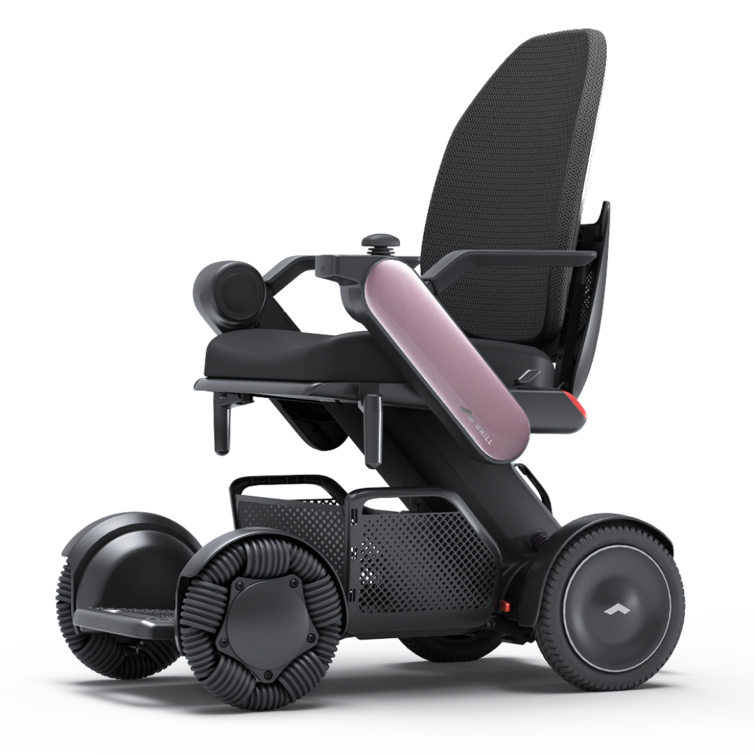 The Whill Model C2 High Back Smart Power Chair with RC App Control, in black, features large distinctive wheels, a mesh backrest, and a sleek curved pink side panel, showcased against a plain white background for clear presentation.