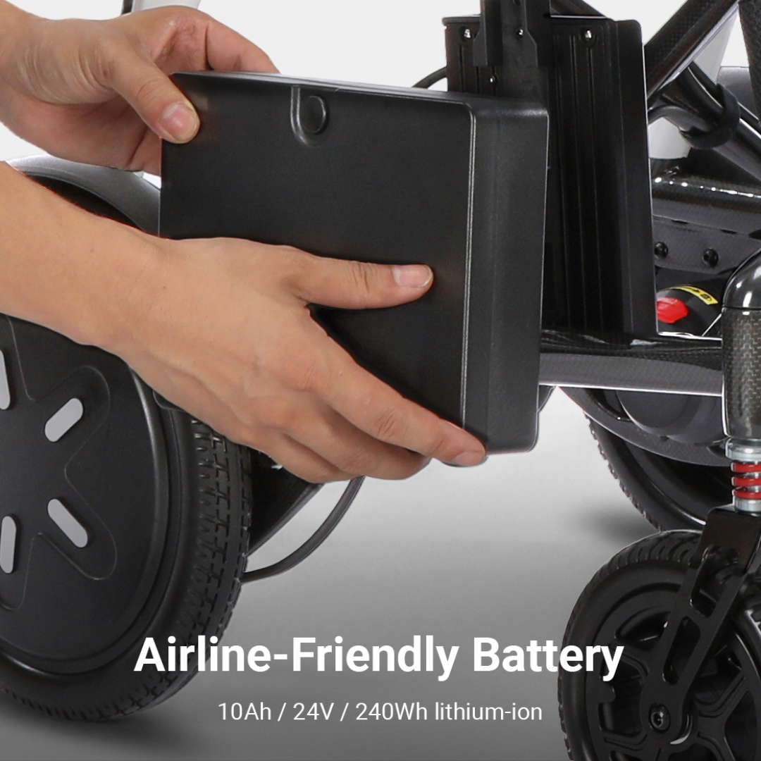 Close-up of hands inserting a rectangular black battery into a slot on a mobility device, with wheels visible. Text reads: Airline-Friendly Battery 10Ah / 24V / 240Wh lithium-ion. Perfect for the Whill MODO Breeze Ultra-Lightweight CF Folding Electric Wheelchair—this foldable powerchair offers travel-ready convenience and reliable energy for your journeys.