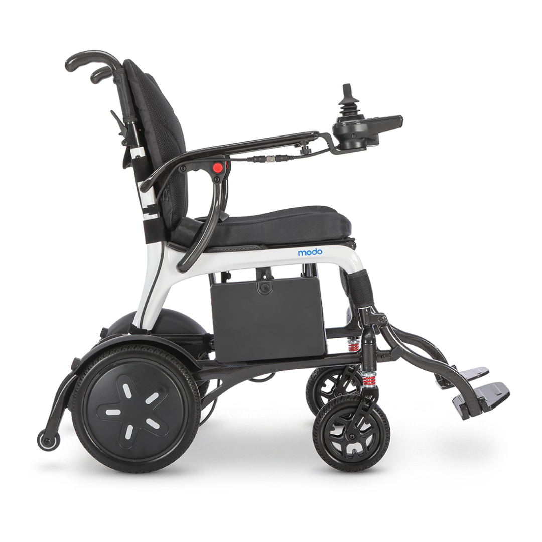 A side view of the Whill MODO Breeze Ultra-Lightweight CF Folding Electric Wheelchair, featuring a joystick control, black seat, armrests, and footrests. This foldable electric wheelchair is equipped with large rear wheels and small front wheels, designed for superior mobility and comfort.