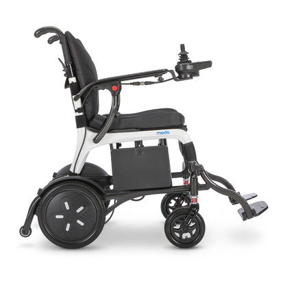 A side view of the Whill MODO Breeze Ultra-Lightweight CF Folding Electric Wheelchair, featuring a joystick control, black seat, armrests, and footrests. This foldable electric wheelchair is equipped with large rear wheels and small front wheels, designed for superior mobility and comfort.