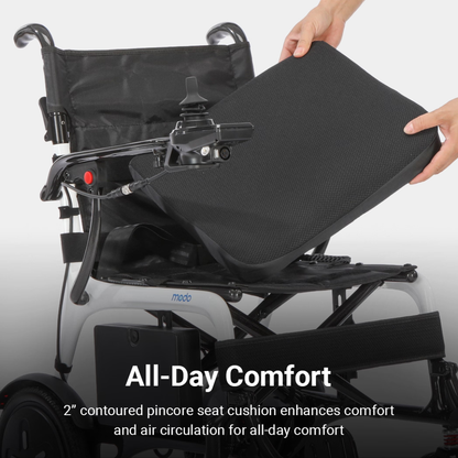 A person lifts a black cushion from a Whill MODO Breeze Ultra-Lightweight CF Folding Electric Wheelchair. Text reads: All-Day Comfort. The 2” contoured pincore seat cushion enhances comfort and air circulation for all-day use, making this ultra-lightweight powerchair perfect for everyday mobility.