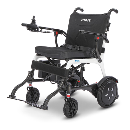 Introducing the Whill MODO Breeze Ultra-Lightweight CF Folding Electric Wheelchair: a modern mobility solution featuring a black seat, armrests, footrests, and intuitive joystick controls. Its white frame complements the compact design with four wheels for stability, while its foldable construction allows for easy storage and transport.