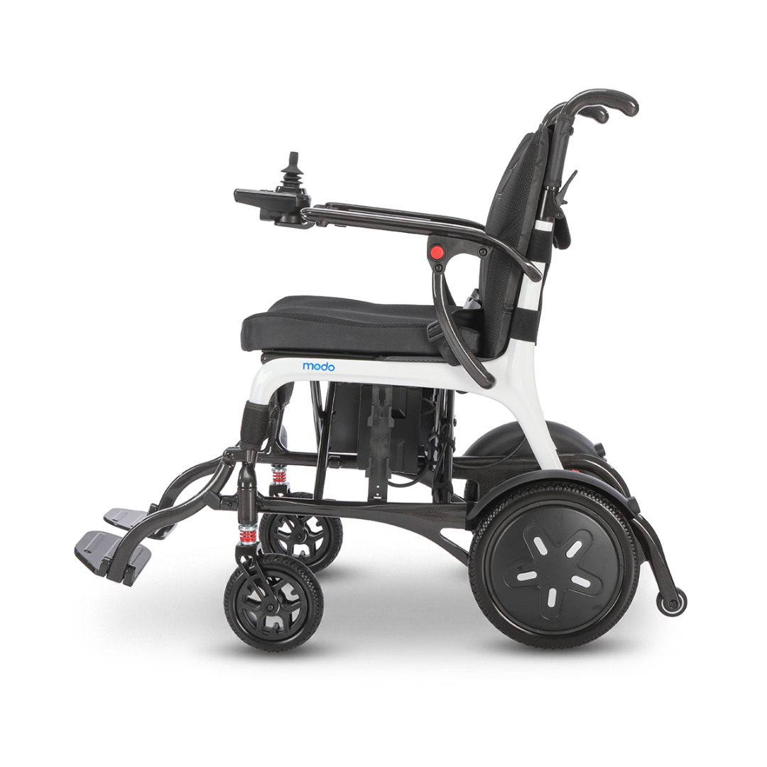The Whill MODO Breeze Ultra-Lightweight CF Folding Electric Wheelchair, featuring joystick control, footrests, and large rear wheels, is shown in a side profile against a white background.
