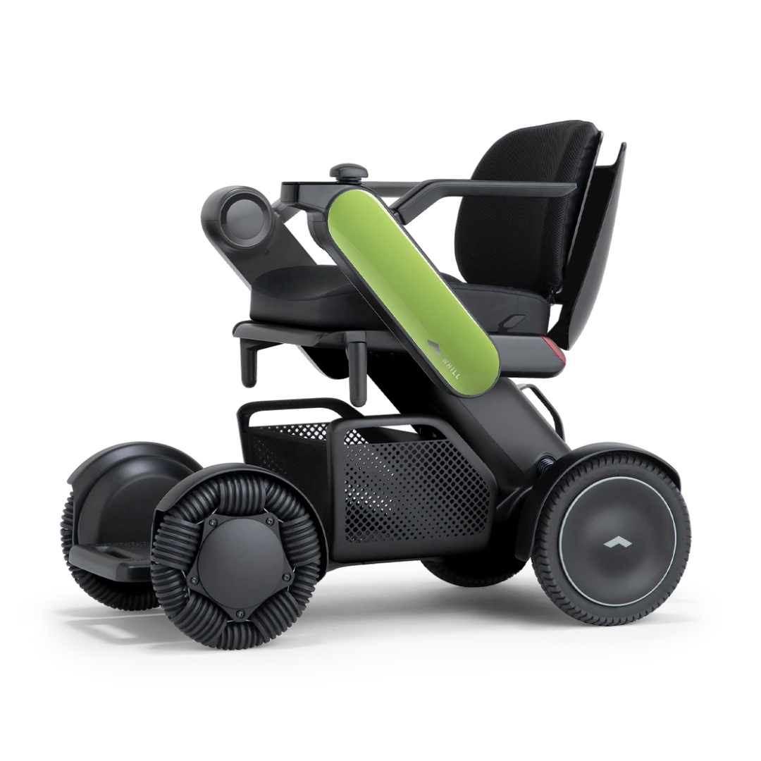 The Whill Model C2 Smart Power Chair is a modern, compact electric wheelchair with large wheels, green armrest accents, a mesh basket under the seat, and is FDA-compliant as a Class II medical device.