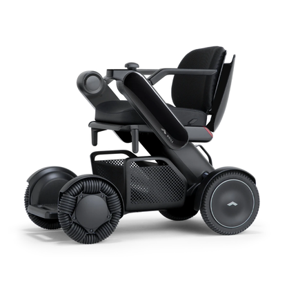 The Whill Model C2 Smart Power Chair is a compact, portable mobility device with four all-terrain wheels, mesh under-seat storage, padded armrests, a minimalist black design, and FDA Class II medical device compliance.