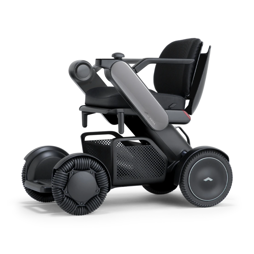 The Whill Model C2 Smart Power Chair is a compact, portable mobility device featuring four large wheels, a cushioned seat, armrests, and an under-seat basket. This sleek black Class II medical chair meets FDA standards for safety and comfort.