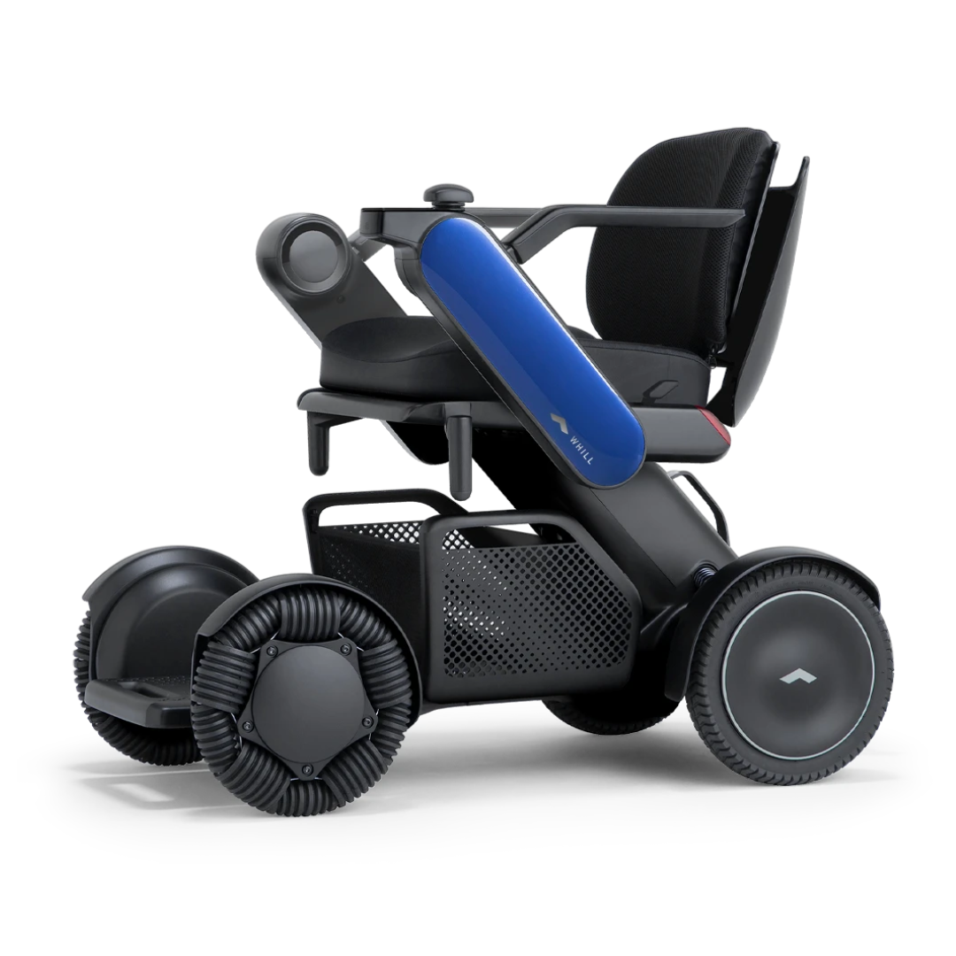 The Whill Model C2 Smart Power Chair is a modern, compact electric wheelchair with a sleek black frame, blue side accent, mesh storage basket, cushioned seat and backrest, and four multidirectional wheels; FDA Class II compliant.