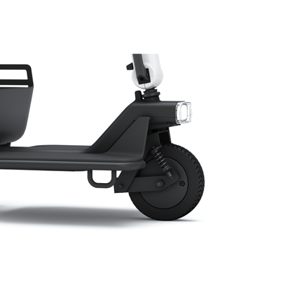 Close-up view of the Whill Model R 3-Wheel Mobility Scooter’s front wheel, black frame, suspension system, and rectangular headlight on a white background.