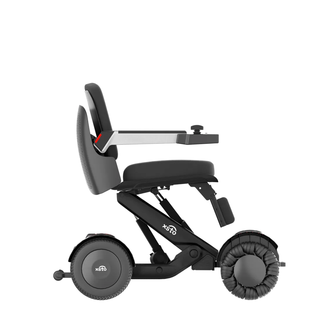 The XSTO Mobility M4 Self-Balancing Powerchair, shown in side profile against a white background, features a compact black and gray frame, padded seat and backrest, armrests, joystick control, and large rear wheels.