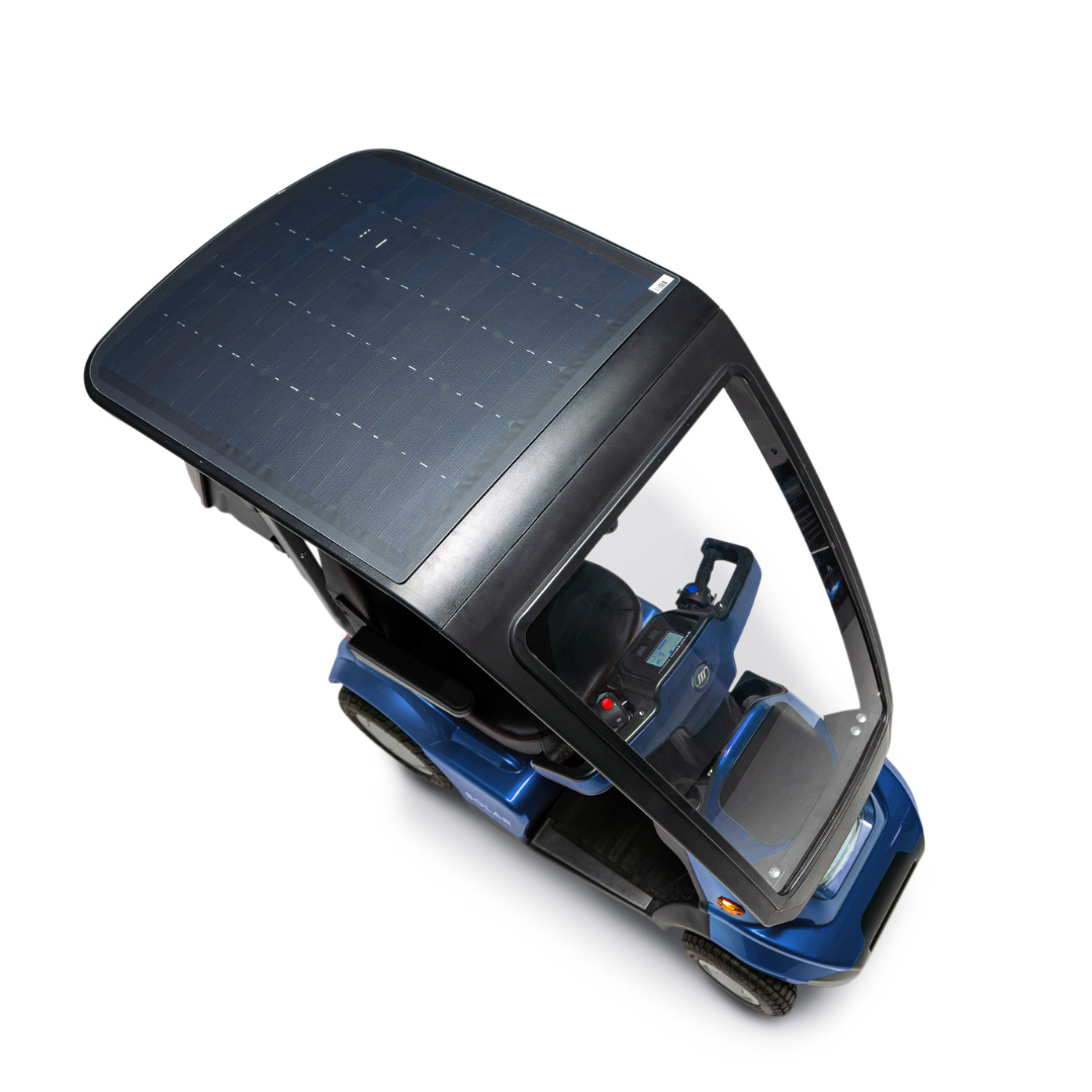 The Afikim Afiscooter Solar, a blue bariatric mobility scooter, features a large solar panel canopy and transparent windshield. It offers seating and steering wheel visibility from above, highlighting its efficient solar charging as the panel extends across almost the entire roof.