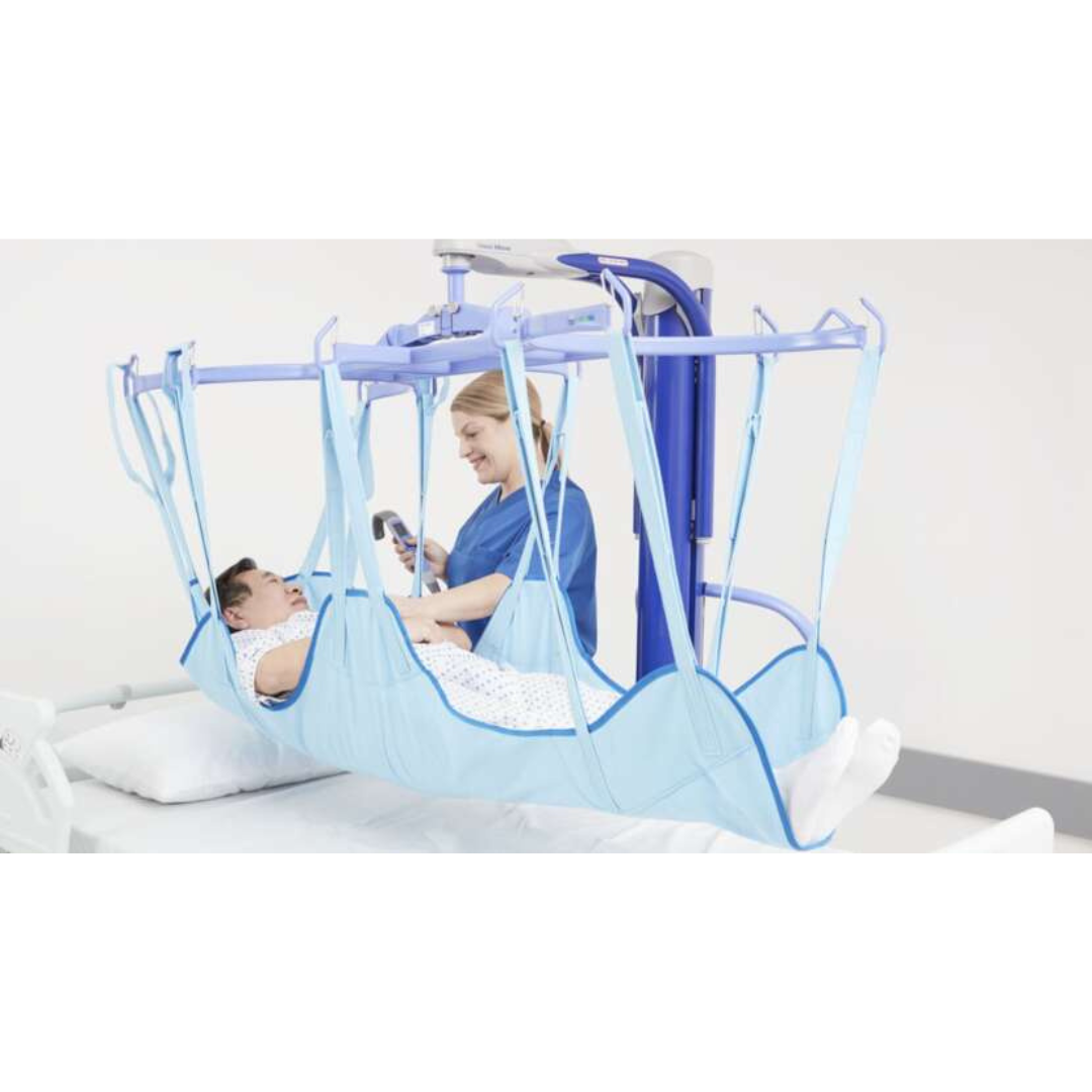 A healthcare worker uses the ARJO Maxi Move Electric Floor Lifter & All-Purpose Patient Lift to safely transfer a patient in a blue sling above a hospital bed. The caregiver smiles as they assist, and the patient looks calm during the process.