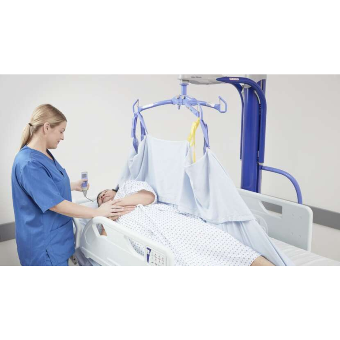 A healthcare worker in blue scrubs uses the ARJO Maxi Move Electric Floor Lifter & All-Purpose Patient Lift to safely and comfortably transfer a patient in a hospital bed with a support sheet in a clinical setting.